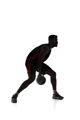 Silhouette of man, basketball player in motion during game, dribble ball, training isolated on white background. Concept of professional sport, competition, game, tournament, action