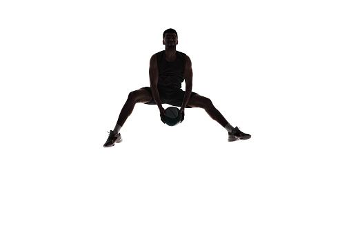 Silhouette of male athlete, basketball player in mid-air training, playing isolated on white background. Dynamics. Concept of professional sport, competition, game, tournament, action