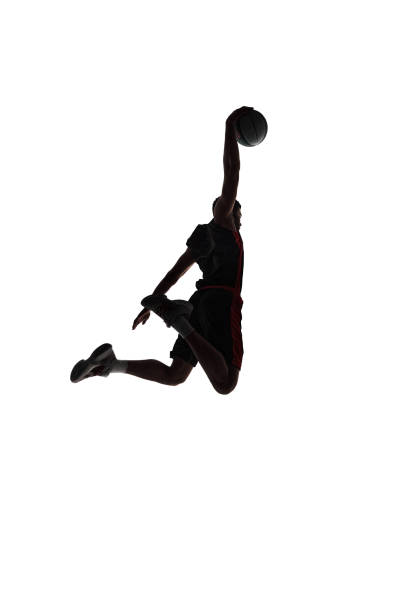Slam dunk. Back view silhouette of young man, basketball player in motion throwing ball during game isolated on white background Slam dunk. Back view silhouette of young man, basketball player in motion throwing ball during game isolated on white background. Concept of professional sport, competition, game, tournament, action silhouette of basketball player slam dunk stock pictures, royalty-free photos & images