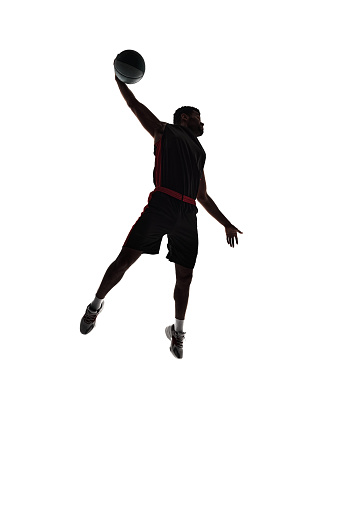 Full-length silhouette of male basketball player, athlete in motion during game, making winning moment isolated on white background. Concept of professional sport, competition, game, tournament