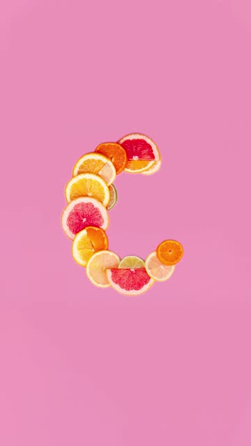 Vitamin C on pink background, slice of citrus orange, lemon flat lay creative composition stopmotion video animation vertical 4k