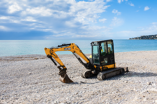 Menton, France - April 9, 2024: The excavator of the company JCB on the beach of Menton.