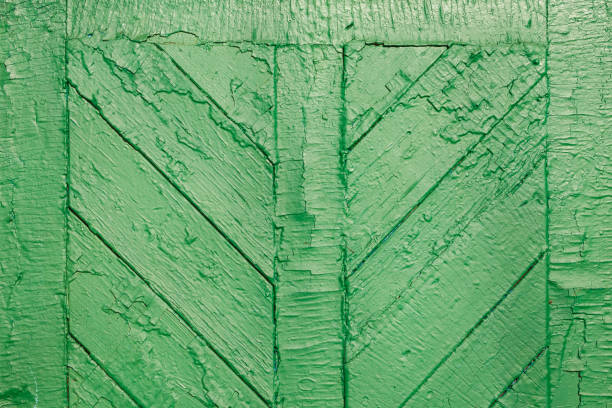 The old wooden surface is painted with green oil paint. Close-up. Texture. Abstract background. Old door