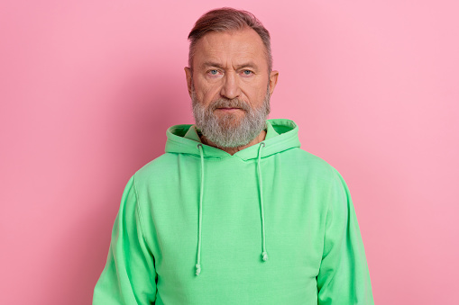Photo of serious confident man wear green sweatshirt looking you isolated pink color background.