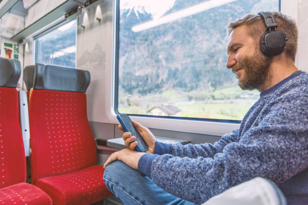 istock Young man on a train enjoying music on his mobile device 2148365773
