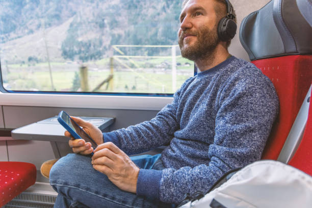 istock Young man on a train listening to music through his headset 2148365796