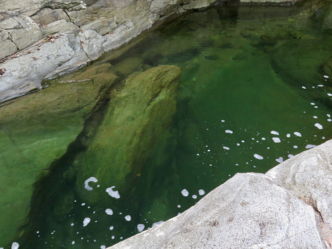 View of the rocky bottom of the river through the transparent water.