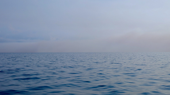 Fog over the water. View of the calm surface of the ocean on a cloudy day.