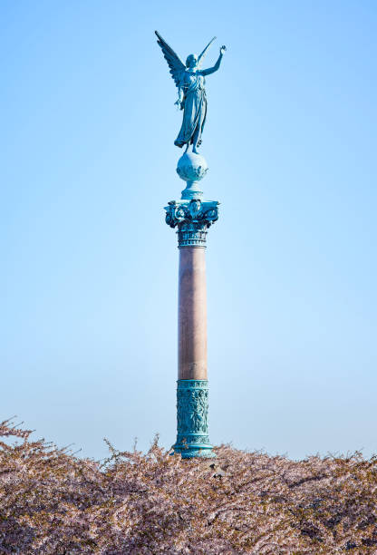 istock Angelic statue for the fallen in war saluting high on a column above blooming pink cherry flowers commemorates the death of Admiral Ivar Huitfeldt (1886) in a Naval Battle or war. Copenhagen, Denmark 2148366160