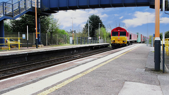 April 12nd. 2024. A diesel freightliner locomotive is pulling a goods / freight train at Widney Manor Station West Midlands, England UK. It is a sunny day in Spring and there are no people in the picture.