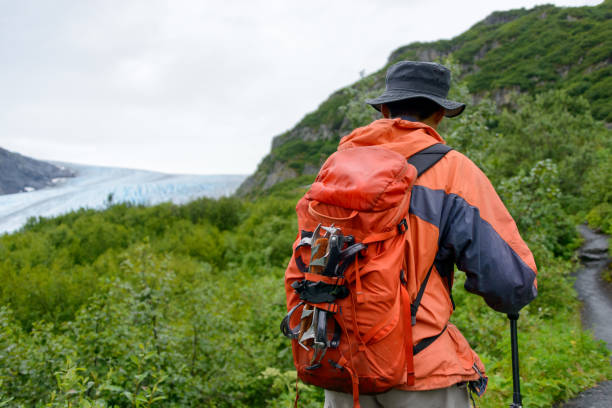 Mountaineer with a large backpack stands on the snowy slopes of chimborazo, admiring the view