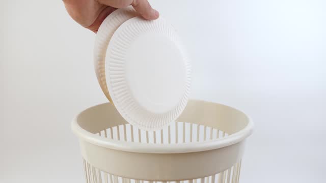Disposable paper plates are thrown into the trash. Disposal of household waste.