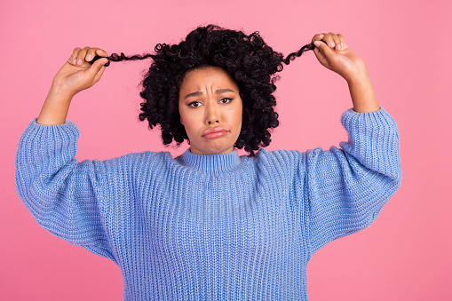 Photo portrait of lovely young lady hold unhappy hair strand wear trendy blue knitted garment isolated on pink color background.