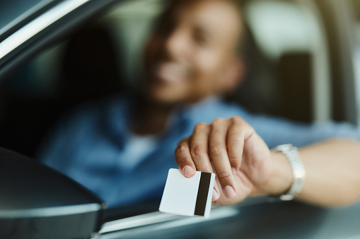 Close up of unrecognizable man showing his driver's license while driving a car.
