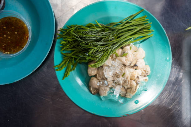 Raw and fresh oyster served with acacia leaves. Thai food popular seafood menu.