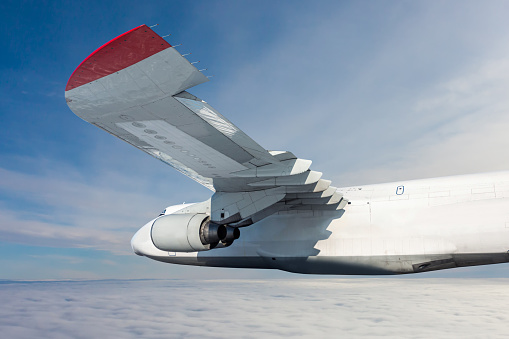 White wide body transport cargo aircraft fly in the air above the clouds