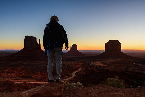 A tourist man waits for the sunrise in Monument Valley, USA, traveling during winter in Arizona