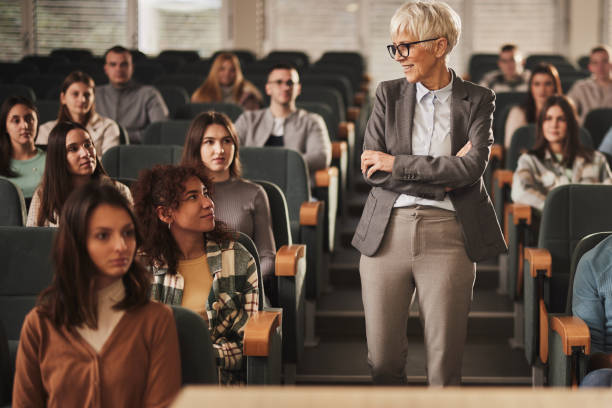 istock Happy senior professor talking to her students on a class at lecture hall. 2148370617