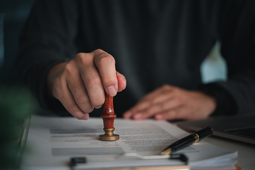 Focused individual placing a seal on an official document with red wax stamp in a professional setting