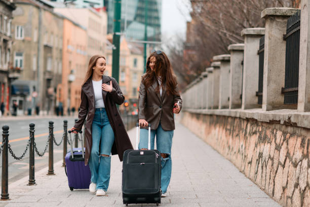 istock Two female tourists explore a European city, pulling their suitcases along as they wander through the charming streets, immersing themselves in the culture and beauty of their travel destination 2148371035