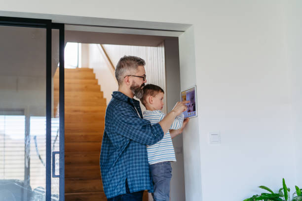 istock Father showing son smart home system, adjusting household functions, lighting, security cameras, door locks and smart thermostat or heating settings. Concept of sustainable and smart technology in home. 2148371210