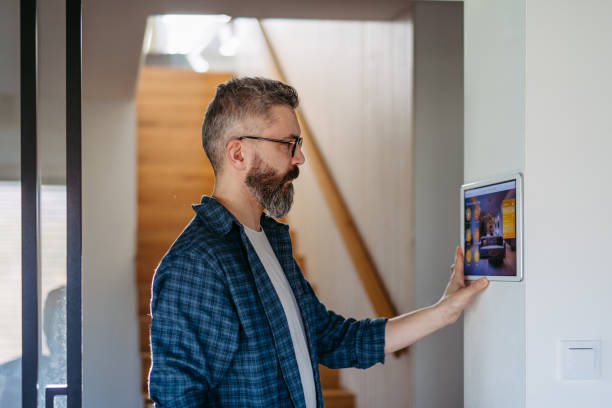istock Smart home system. Man adjusting household functions, lighting, security cameras, door locks and smart thermostat or heating settings. Concept of sustainable and smart technology at home. 2148371418