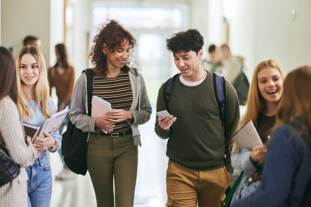 istock Happy college couple using cell phone in a hallway. 2148371671