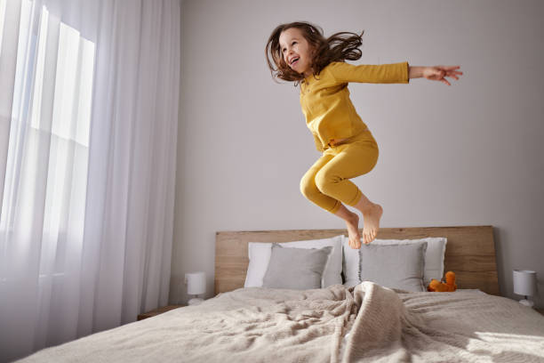 istock Carefree girl having fun while jumping on the bed. 2148372151