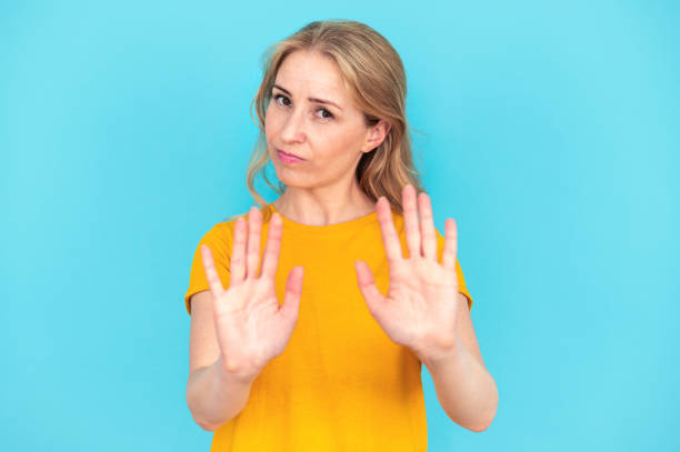 istock Woman showing stop gesture by hands on blue background 2148373156