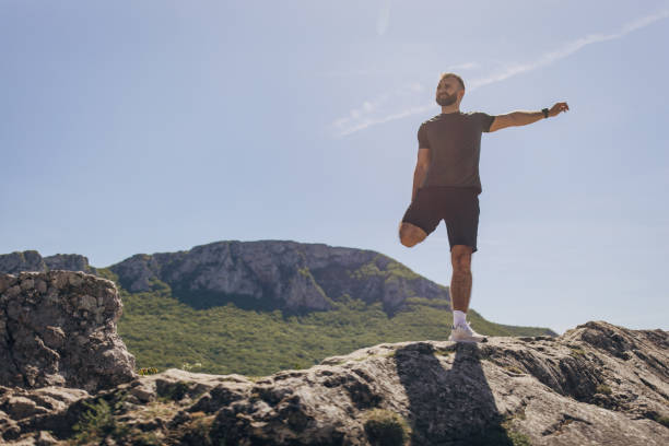 Mid adult man warming up and stretching before mountain running