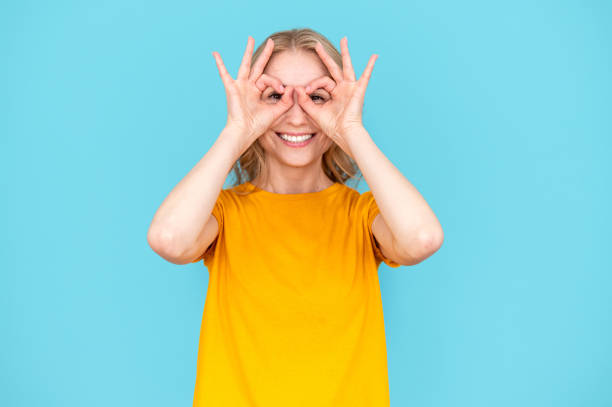 istock Happy woman making finger glasses at eyes on blue background. 2148373411