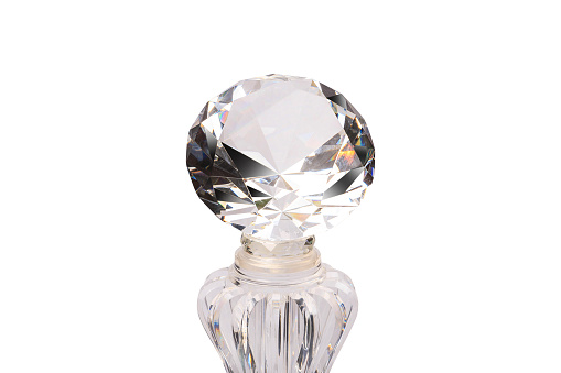 Faceted diamonds reflect bright light on a white background. With a clear glass bottle base underneath.