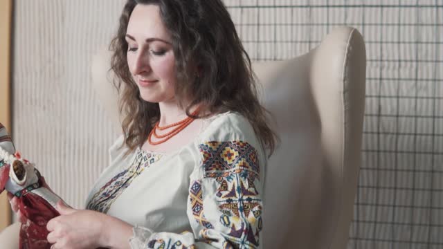 portrait depicts a beautiful young woman in an embroidered authentic Ukrainian shirt holding a handmade motanka doll