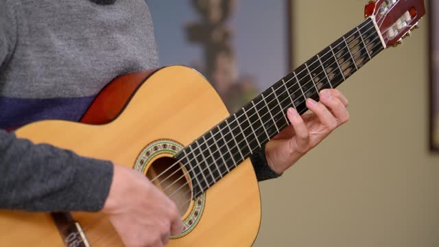 Close-up shot of a man playing scales on a classical guitar