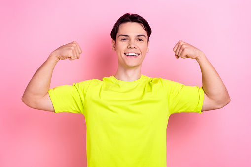 Photo portrait of pretty teenager guy flexing showing muscles dressed stylish yellow outfit isolated on pink color background.