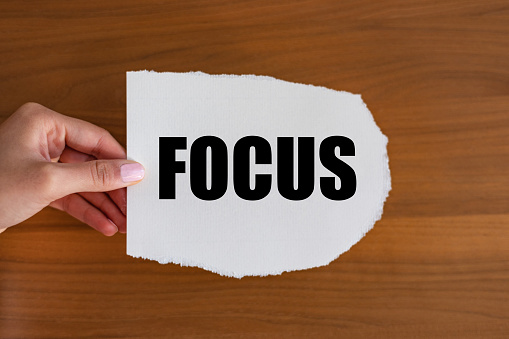 Focus. Woman hand holds a piece of paper with a note, focus. Center, objective, core, aim, nucleus.