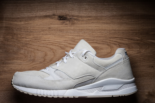 Natural suede white sneakers on wood table