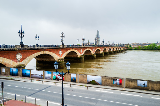 Bordeaux, France - April 7th, 2024: The Pont de pierre bridge in Bordeaux with paintings and photos on the street.