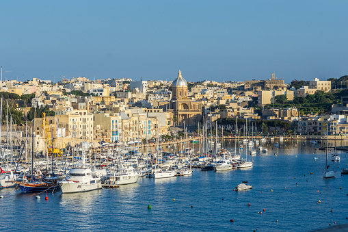 Kalkara, Malta - February 9th 2019: Boats moored at Kalkara Creek with the village and Saint Joseph Church.