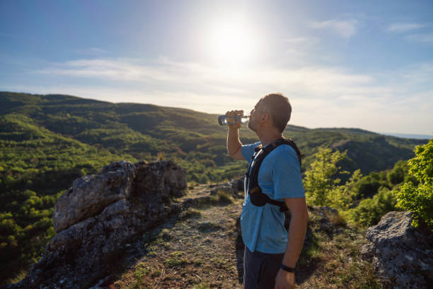 istock Male trail runner taking a short break to drink water 2148379329