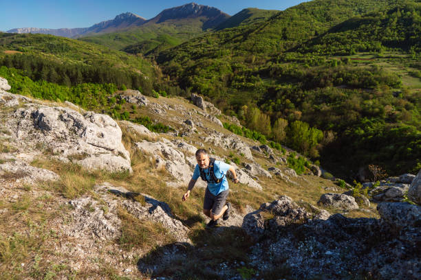 Man running over the rocky mountain trail.