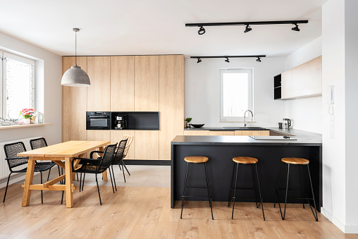 Kitchen in new apartment in modern design with wood, countertop and window. Modern furniture and dining table.