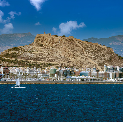 Catamaran sailing in front of the old town of Alicante, with Mount Benacantil and Santa Barbara castle in the background, Spain