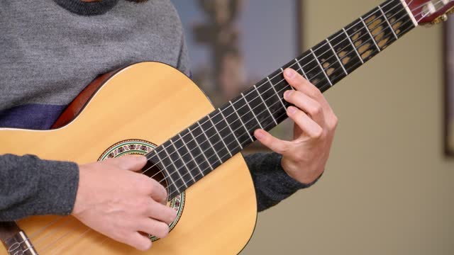 Close-up shot of a man playing a classical guitar