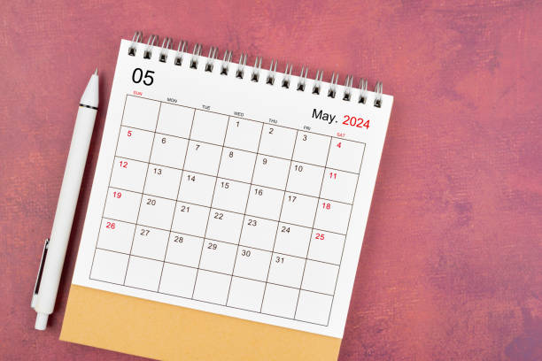 istock May 2024 desk calendar and pen on red background. 2148385419