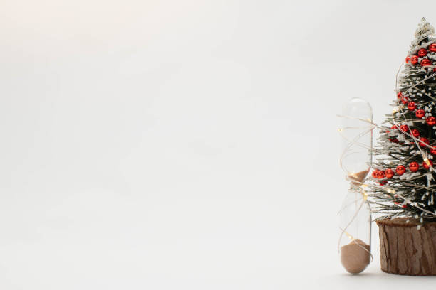 Christmas concept with space for text, Hourglass and Christmas tree is decorated with red garland on white background