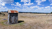 An outback dunny or outhouse sits on the dry and arid farmlands near Yass NSW at the end of summer