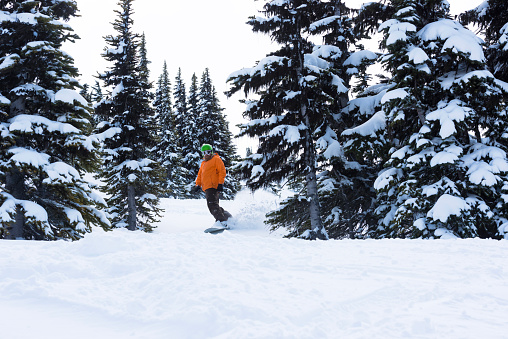 Backcountry snowboarder descends mountain through fresh powder snow
