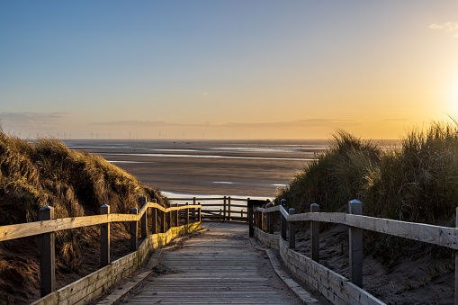 Looking along a a wooden boardwalk leading to the beach, at Formby in Merseyside