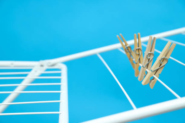 Clothespins hanging on drying rack on blue background